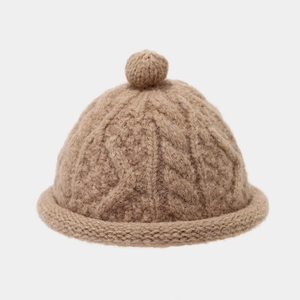 Close-up of camel cable-knit beanie featuring a ribbed cuff and top knit ball detail