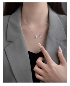 Detailed view of an S925 silver necklace with white pearl and crisscross diamond pendant