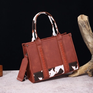 Detailed view of the brown cow print tote bag with woven handles and adjustable strap
