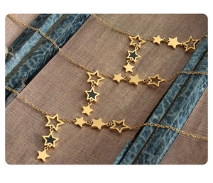 Macro detail of layered star pendant necklace in gold finish with black enamel accents