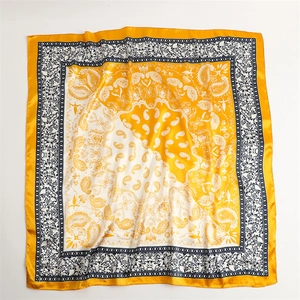 Flat lay of a yellow and white paisley silk scarf with a retro two-tone square pattern