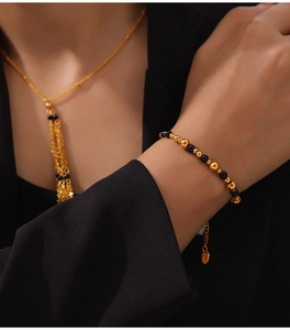 Detail of beaded necklace and chain bracelet in gold and black onyx on stainless steel