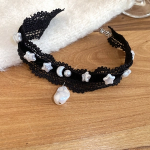 Choker en dentelle avec breloques lune et étoile et perle baroque sur fond en bois