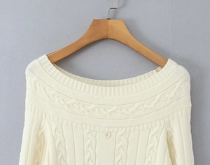Gros plan sur le pull en maille blanc crème avec motif torsadé et bouton au col rond