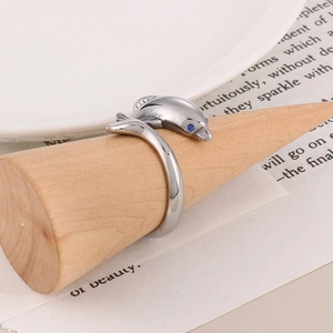 Detail of silver dolphin ring with blue crystal eyes on a wooden display stand