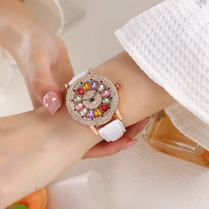 Close-up of a women's rose gold watch with sparkling rhinestones and a white leather strap