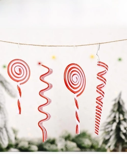 Close-up of red and white acrylic candy cane ornaments hanging on a rustic rope