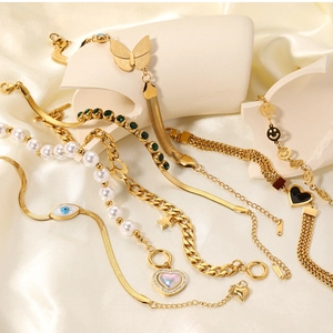 Detail of gold-plated stainless steel charm bracelets with pearls and colorful pendants