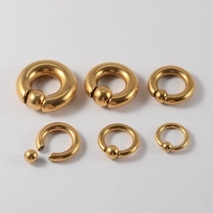 Golden stainless steel BCR spring ball nose rings in three sizes on white background