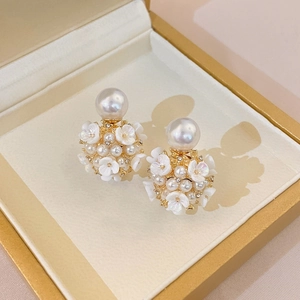 Vue macro d'une boucle d'oreille fleurie avec perles et fleurs blanches en écrin doré