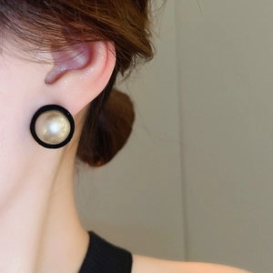 Detail of elegant champagne faux pearl earring with black velvet trim on female ear