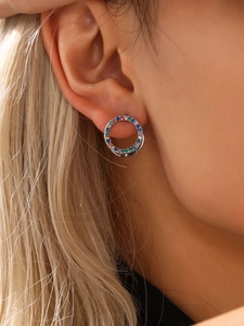 Detalle de un pendiente de aro dorado con circonitas multicolores en la oreja de modelo
