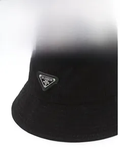 Detailed view of black corduroy bucket hat with wide brim and metal triangle logo
