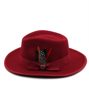 Detail of dark red wool fedora hat featuring decorative feather and metal anchor pin