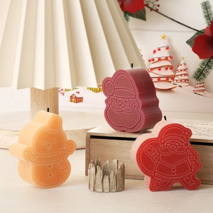 Détail de bougies Père Noël et bonhomme de neige mats sur plateau en bois festif