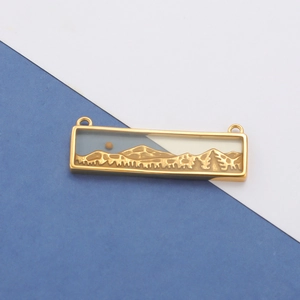 Detail of rectangular gold enamel charm featuring a blue landscape design with two loops