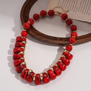 Detailed close-up of red marble acrylic beads and golden metal spacers on a retro necklace