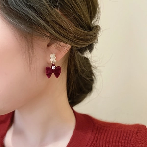 Détail d'une boucle d'oreille nœud en velours rouge avec accents dorés et zircon brillant