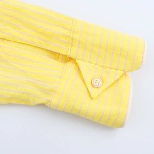 Dettaglio del polsino di una camicia gialla a righe con trama del tessuto e bottone