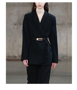 Fine ceinture en cuir noir avec boucle H dorée sur un blazer pour marquer la taille