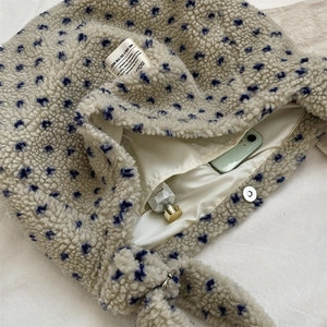 Detail of plush beige tote bag with blue flowers showing magnetic closure and inner lining