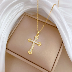 Elegant gold cross necklace with crystal pavé on beige leather box and white silk
