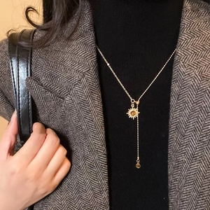 Golden sun pendant necklace with amber stone on model in chic blazer for daily wear