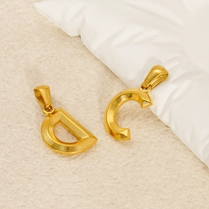 Ciondoli lettere C e D in acciaio al titanio placcato oro 18k su morbido tessuto beige