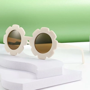 Flower-shaped cream children's sunglasses with dark lenses on a wave display stand