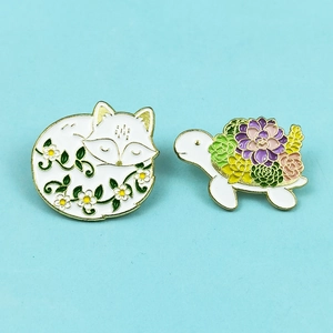 Cute enamel fox and turtle brooches with floral succulent patterns on blue background