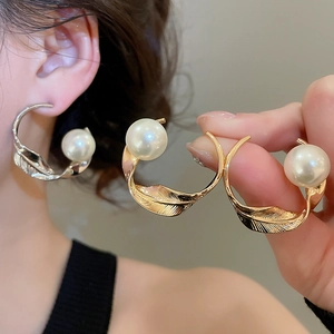 Primo piano di eleganti orecchini di perle con design a foglia intrecciata in oro e argento