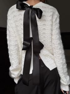 White knit cardigan with a large black bow on the back, elegant hollow out design