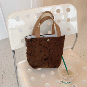 Detailed shot of brown corduroy tote bag with cartoon bear and baby print on a white chair