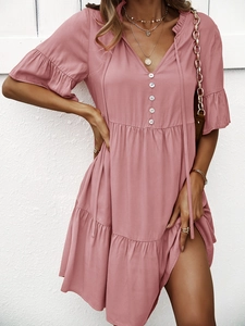 Détail de la robe rose à col en V avec manches courtes, jupe à volants et lien à la taille