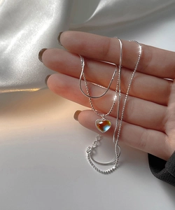 Detail of double-layer necklace featuring moonstone heart pendant on white silk