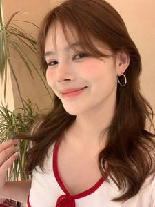 Close-up of minimalist silver hoop earrings worn on ear in a stylish indoor setting