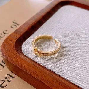 Gold plated H-letter open ring with sparkling cubic zirconia accents on wooden tray