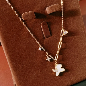 Detail of gold necklace with star and shell swan pendant on brown velvet stand