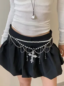 Détail de la chaîne de corps en perles avec pendentif croix en strass sur la taille