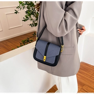 Detail of a contrast stitching saddle bag with gold metal buckle and denim flap texture