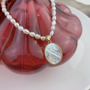 Macro shot of Virgin Mary pendant on pearl necklace over a red crystal glass