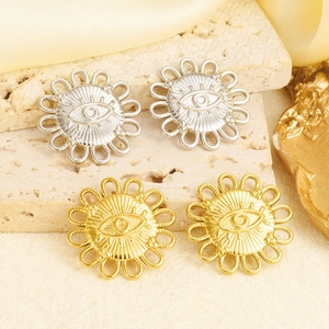 Close-up of gold and silver sunflower evil eye pendants on a textured stone surface
