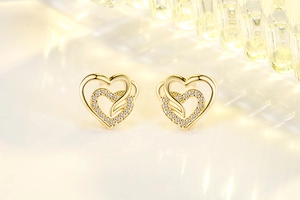 Macro view of double heart stud earrings with sparkling cubic zirconia in gold finish
