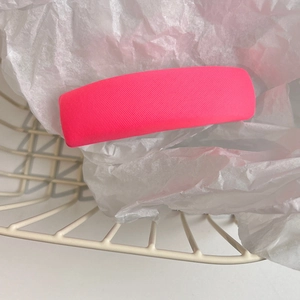 Detail of pink fabric sponge hair clip showing fine diagonal texture on white paper