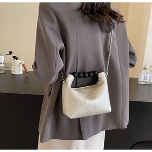 Silver leather dumpling bag featuring black pearl handle and silver chain on model