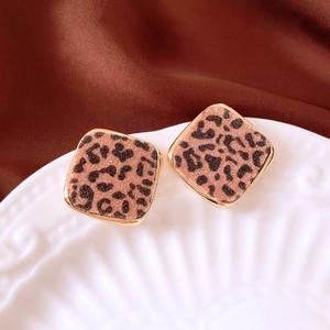 Chic leopard print geometric earrings with gold-plated base on white relief ceramic plate
