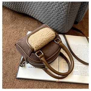 Detail view of brown faux suede handbag with beige lamb wool trim on vintage books