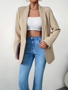 Vue détaillée d'un blazer beige élégant porté avec un haut blanc et un jean bleu