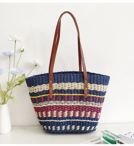 Detail of colorful woven tote bag featuring striped straw texture and brown leather straps