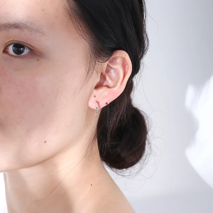 Close-up of gold-plated silver C-shape earring with colorful zircon stones on model's ear